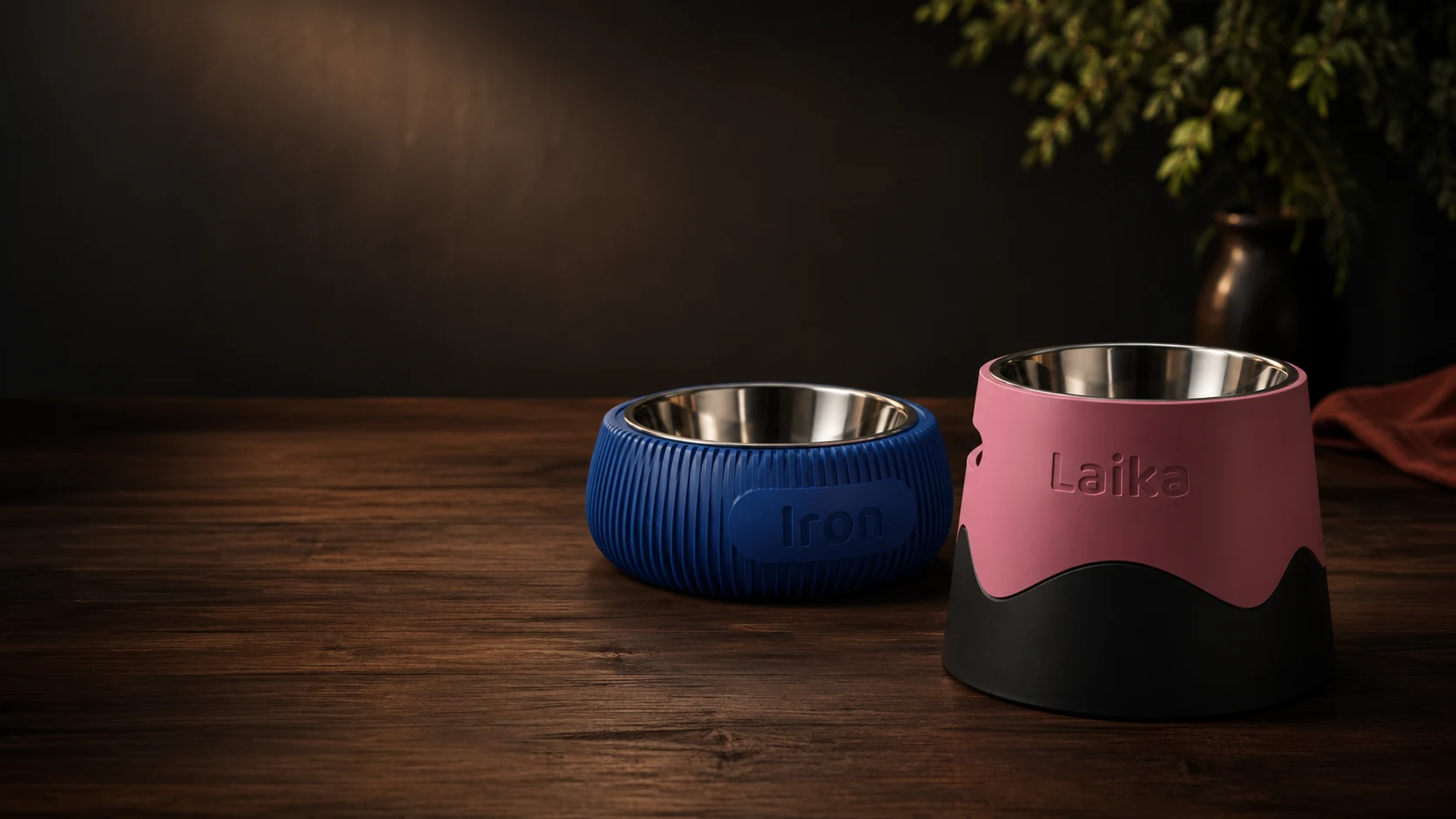 Duas tigelas pet personalizadas em 3D sobre mesa de madeira, uma azul com nome Iron e outra rosa com nome Laika.